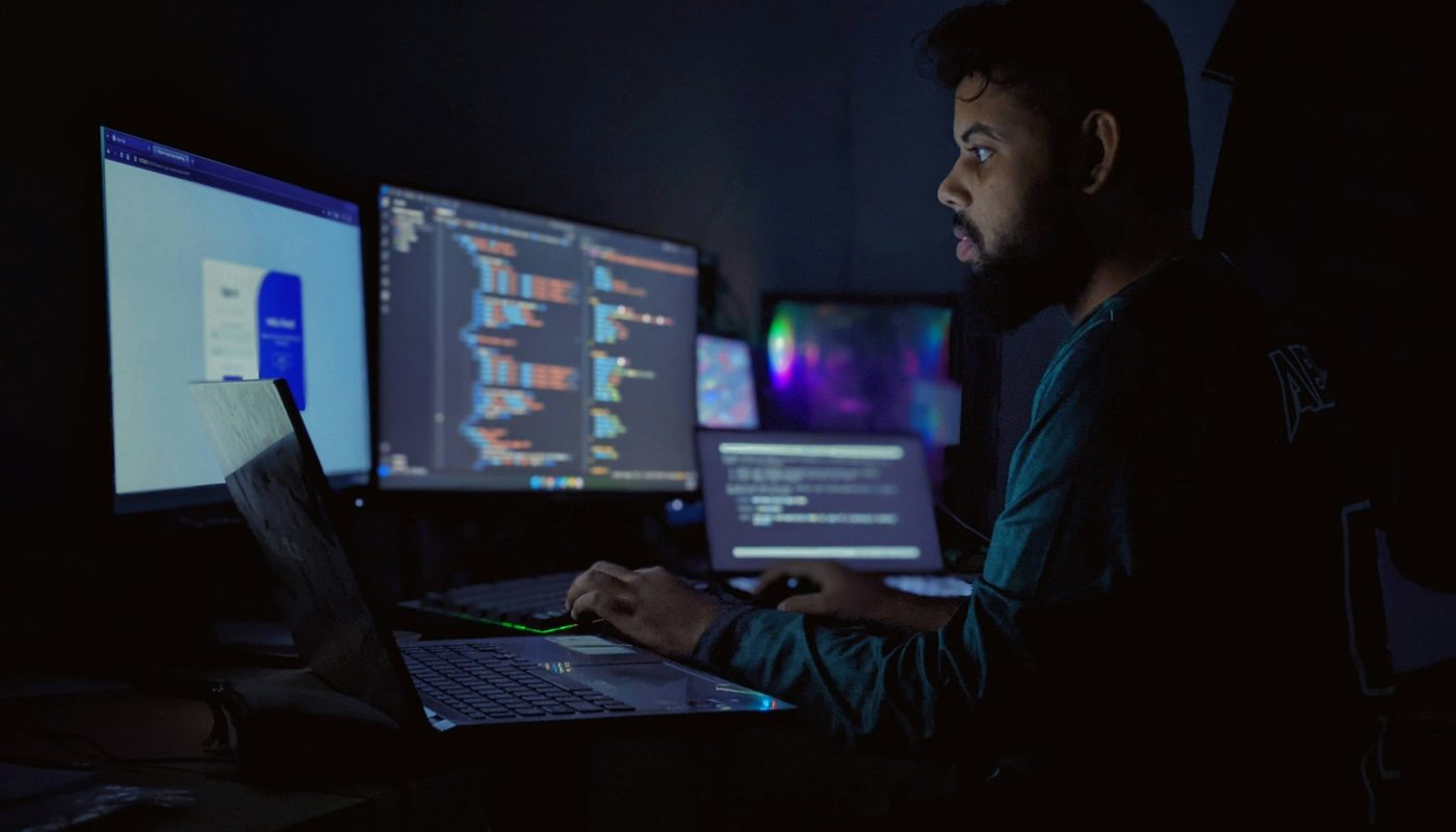 Un desarrollador trabajando frente a varias pantallas con código